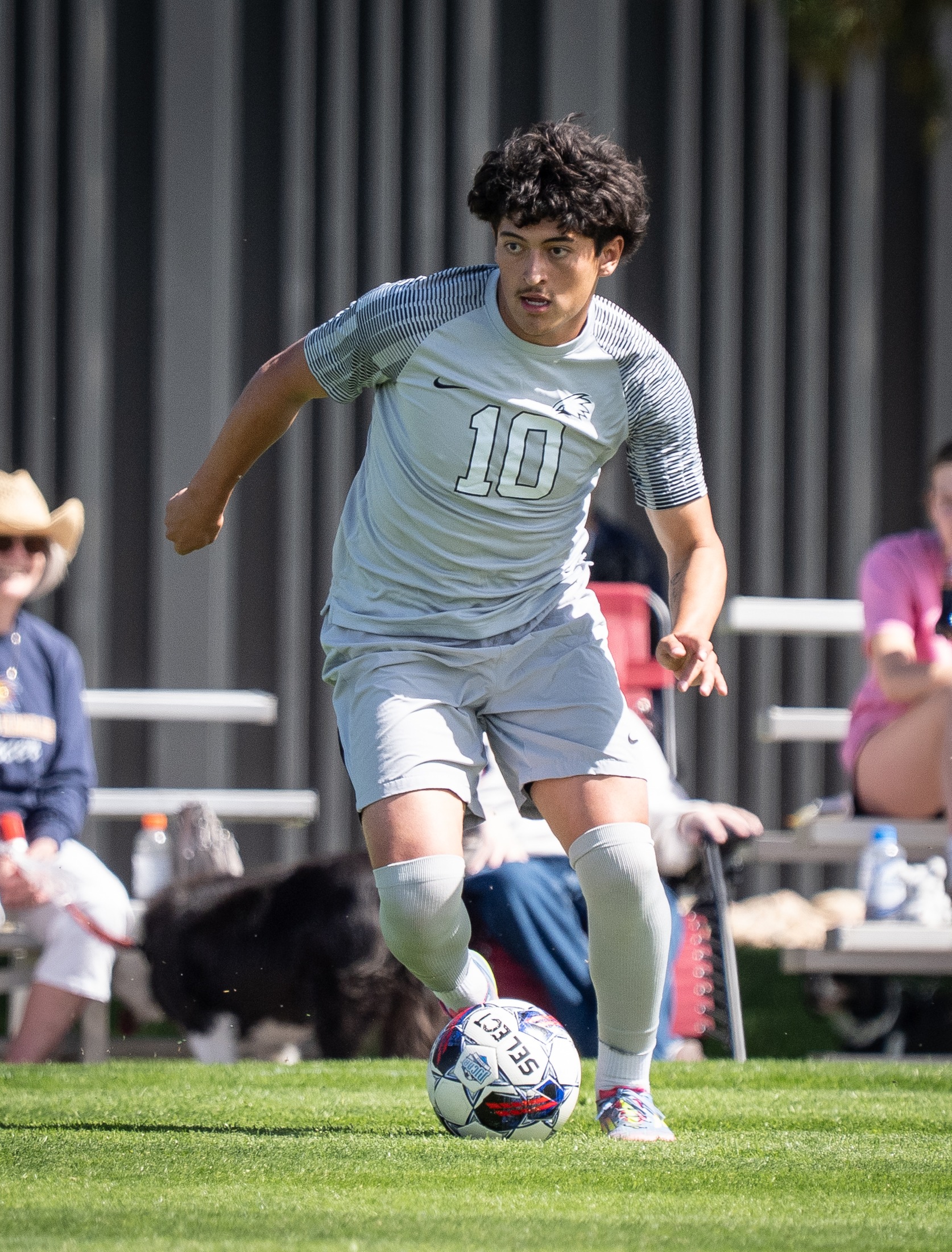 LCCC Men's Soccer Player dribbling the ball Infront of the crowd.  